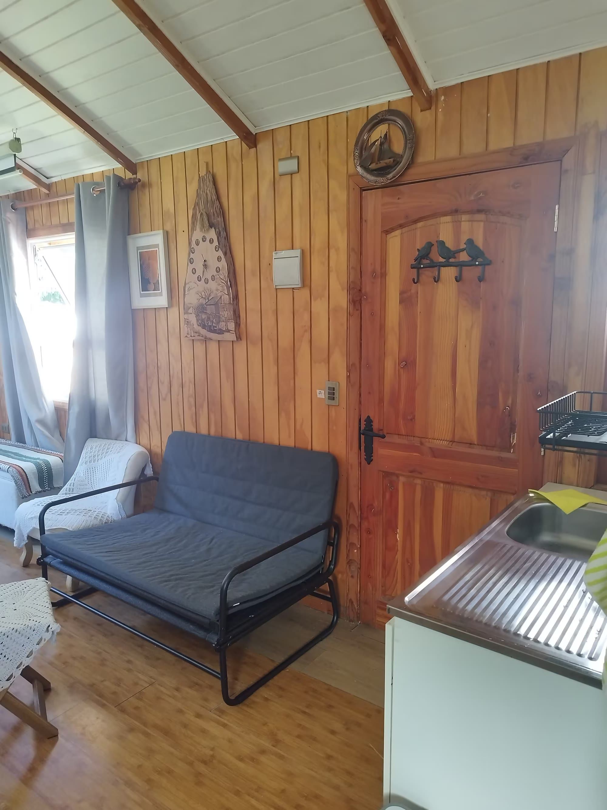 Un sofá cama junto a la ventana y la puerta de madera con perchas de pájaros