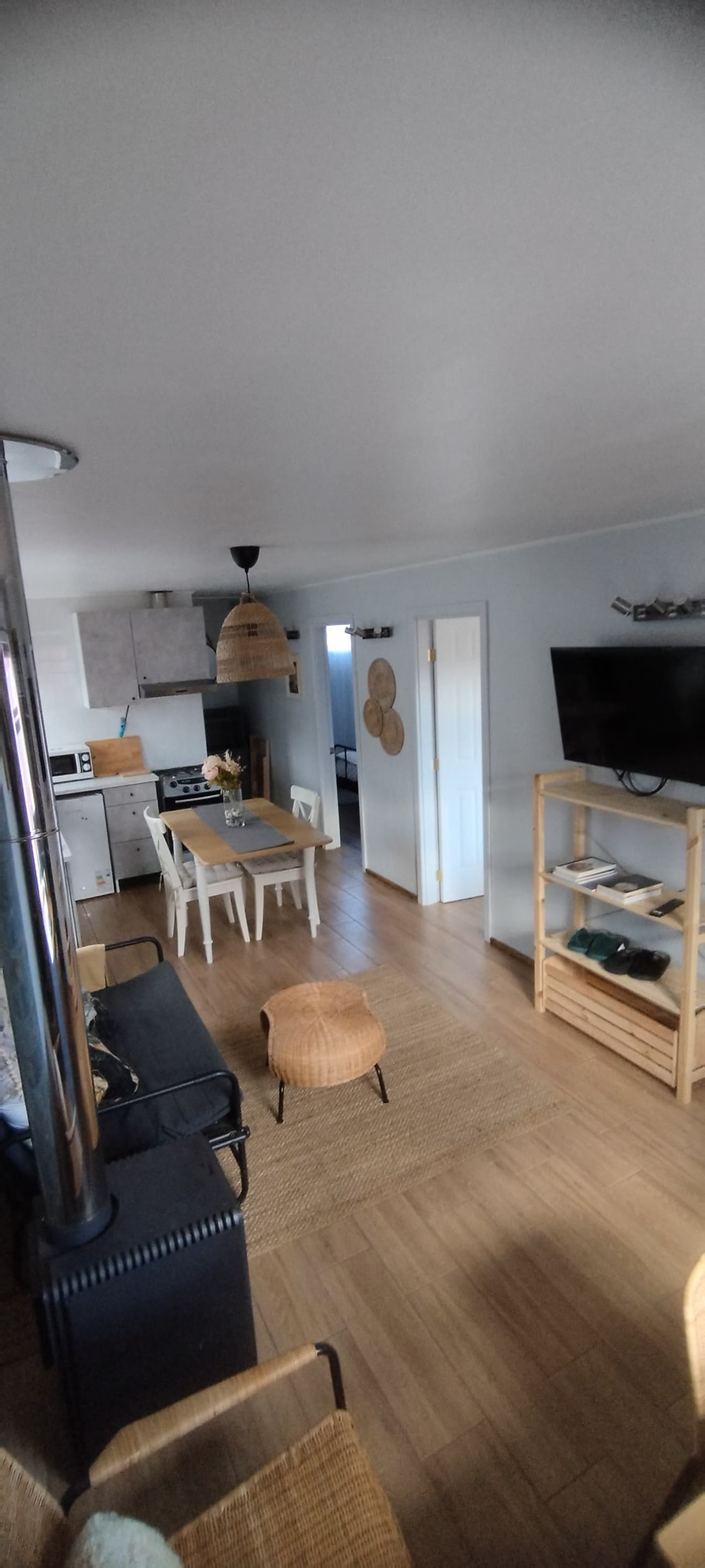 El comedor con mesa de madera, sillas blancas y estantería