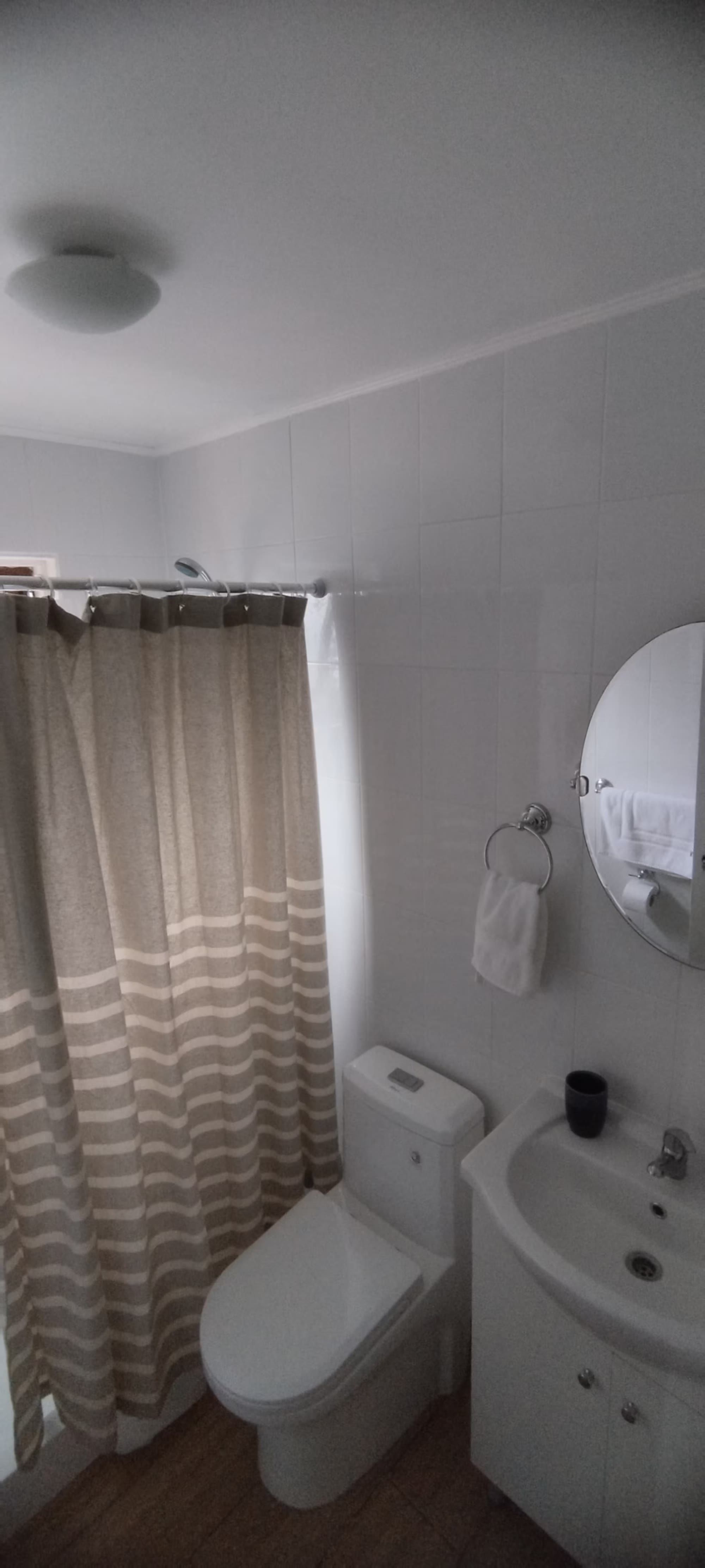 El baño con ducha, espejo redondo y toallas
