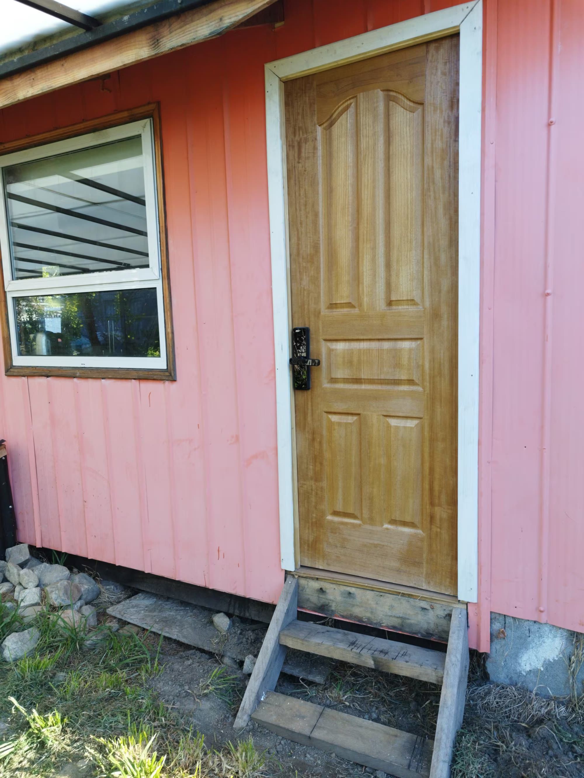 La fachada salmón de La Casita Naranja, con su puerta de madera y cerradura de teclado